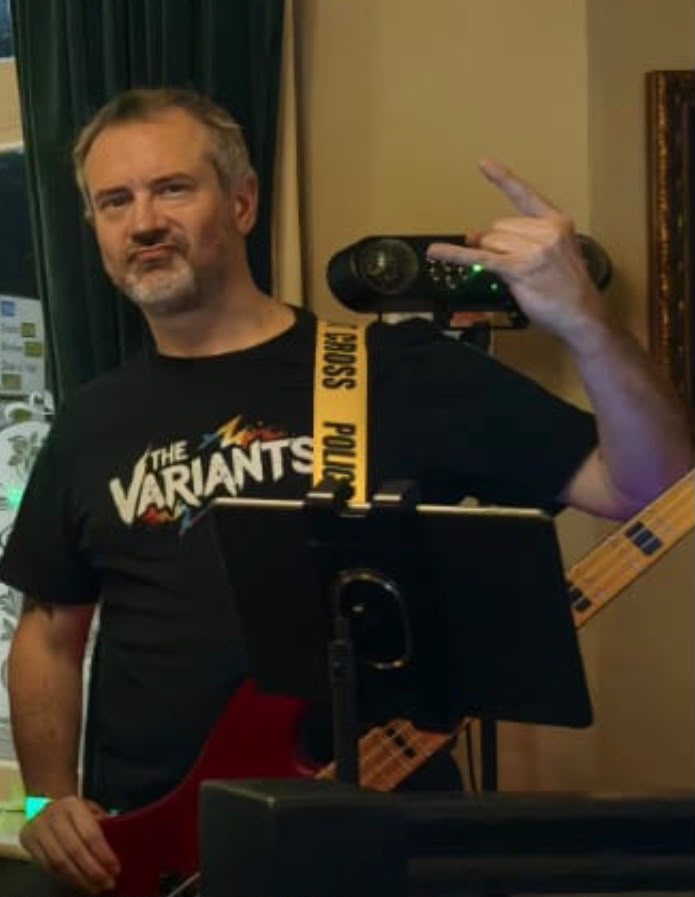 Andy with his bass guitar, raising a rock hand sign