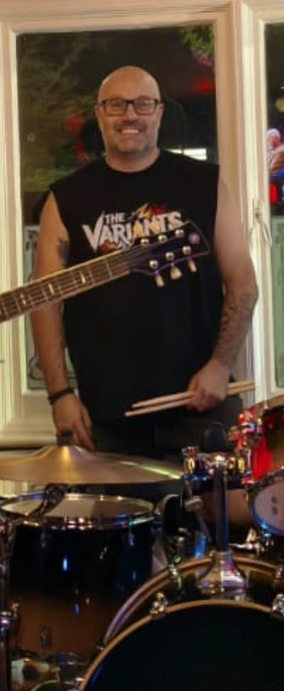 Rich holding drumsticks behind his drum kit
